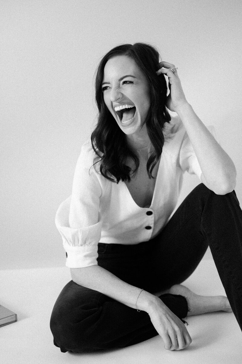 black and white headshot of woman laughing sitting on the floor
