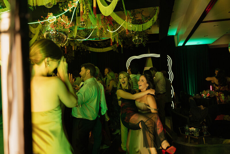 Blurry photo of people dancing at wedding reception with green lights planned by Bloom & Blueprint