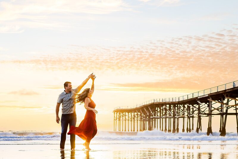 Engagement Portrait showing the couple dancing on the beach at Crystal Pier in Pacific Beach San Diego