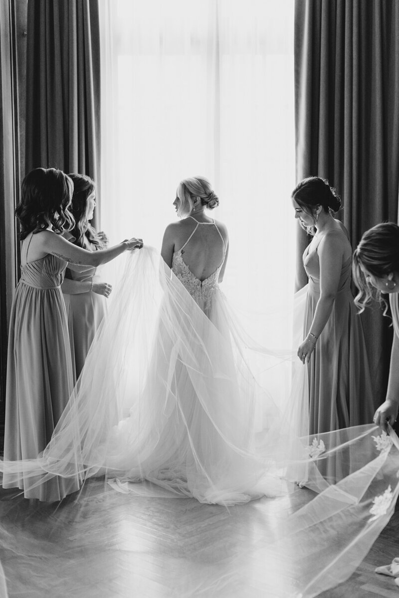 Bridesmaids helping bride with her dress at wedding in Columbus, Ohio