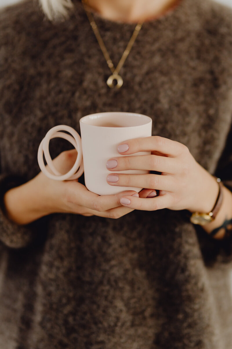 kaboompics_a-woman-in-a-brown-sweater-holds-a-pink-minimalist-mug-10562