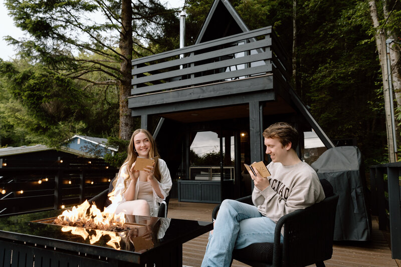 Couple writing vows at their cabin rental in front of a fire.