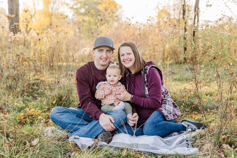 Minooka park Fall family photography session.  Mom and Dad holding Son on blanket in golden hour.