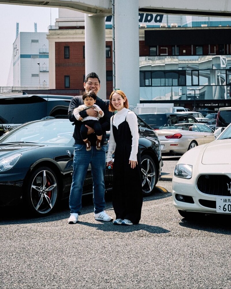 The Sakai family, founders of Tokyo Luxe Drive, stand proudly in front of a luxury Ferrari and Maserati, showcasing their passion for cars and creating unforgettable experiences in Tokyo.