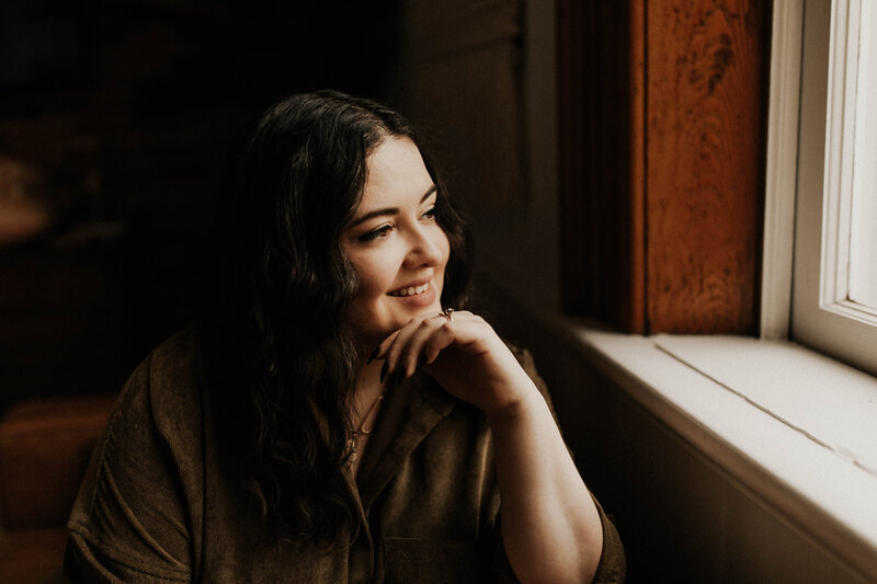 Kris, owner of Femme Collective, looking to the right and smiling 