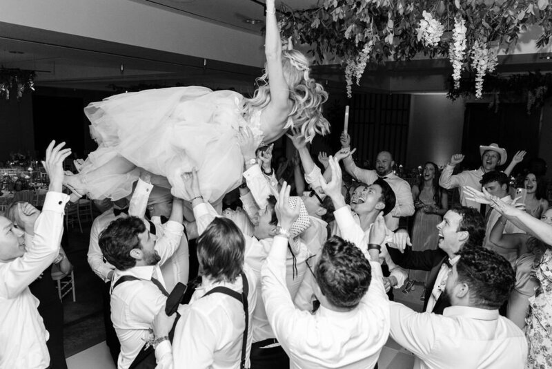 Black and white image of bride being lifted in the air by wedding guests during the wedding reception at Viceroy Resort near Aspen, CO