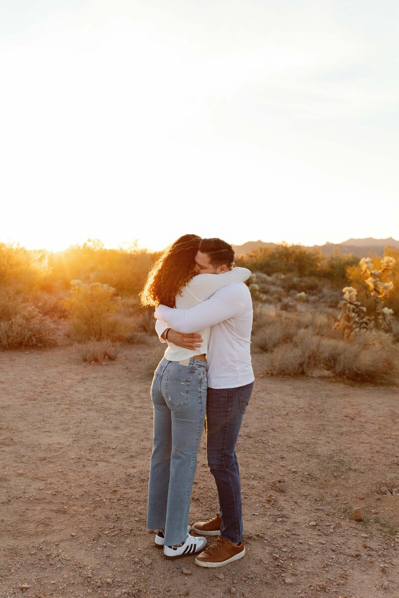 Couple hugs intimately in the Phoenix desert at sunset.