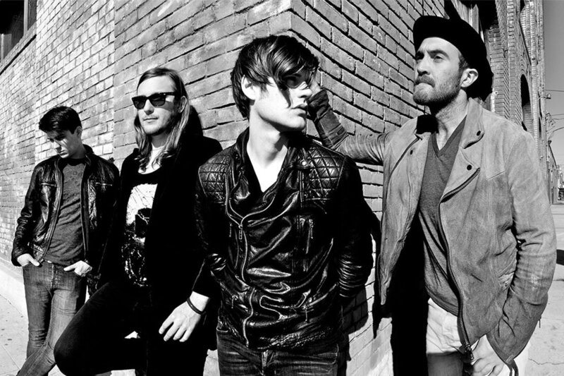 Band portrait The Filthy Souls Los Angeles black and white 4 band members leaning against corner of brick building