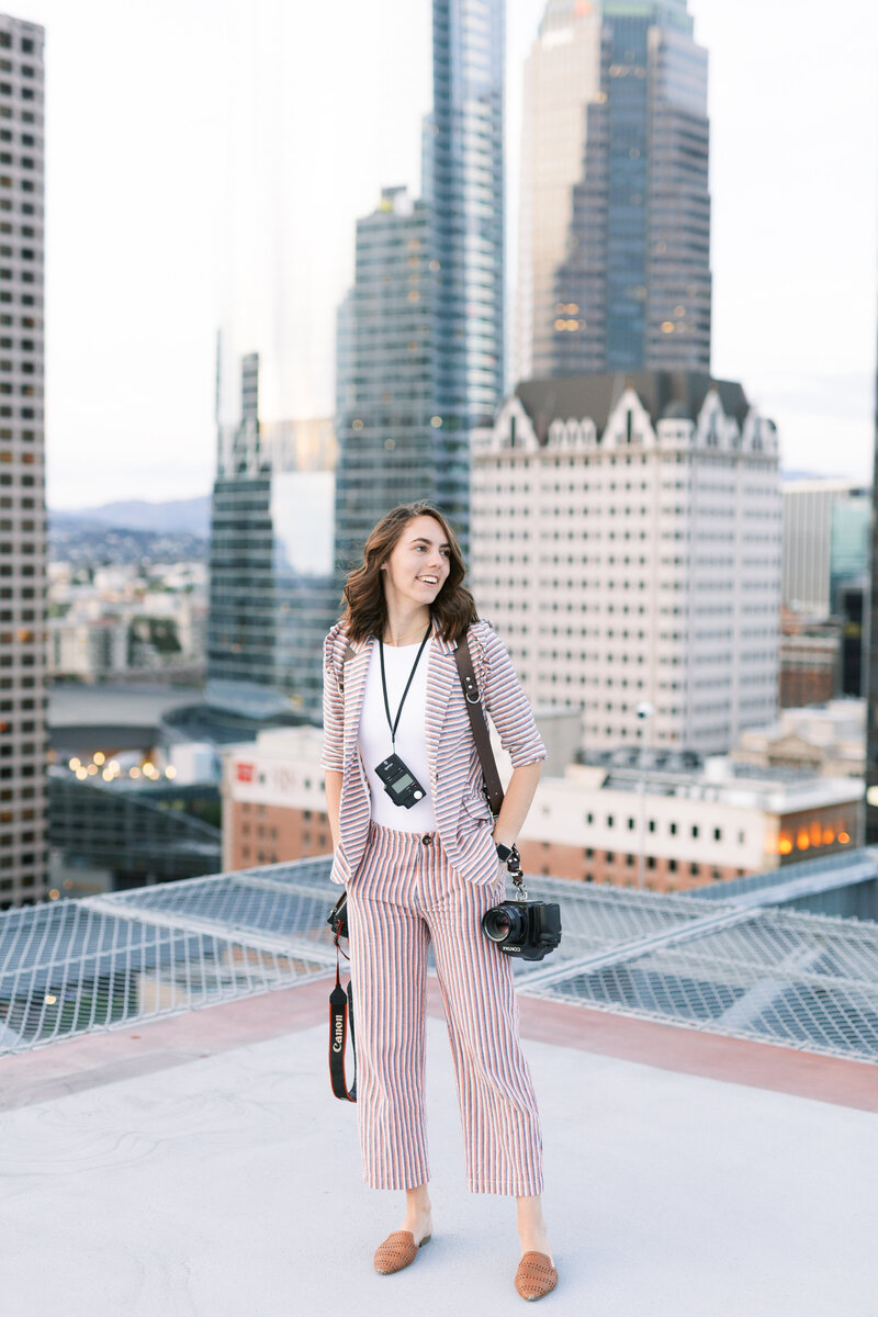 Megan of San Diego Wedding Photographer My Sun and Stars co poses in downtown engagement session location with camera in hand