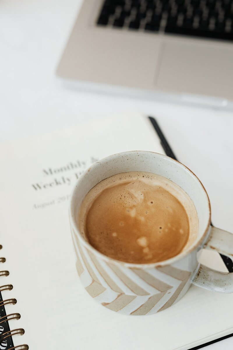 Coffee cup sits next to Pooja's Planner and coaching packages