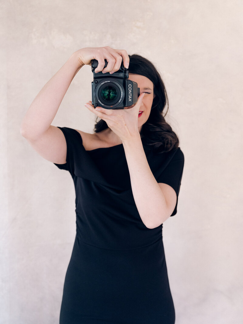 Melissa Schollaert Photographer with camera in black dress