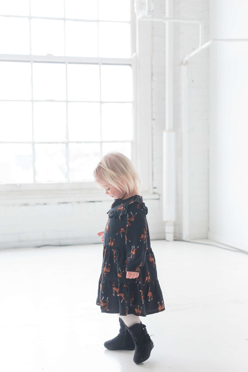 young girl wearing black dress facing away from the camera