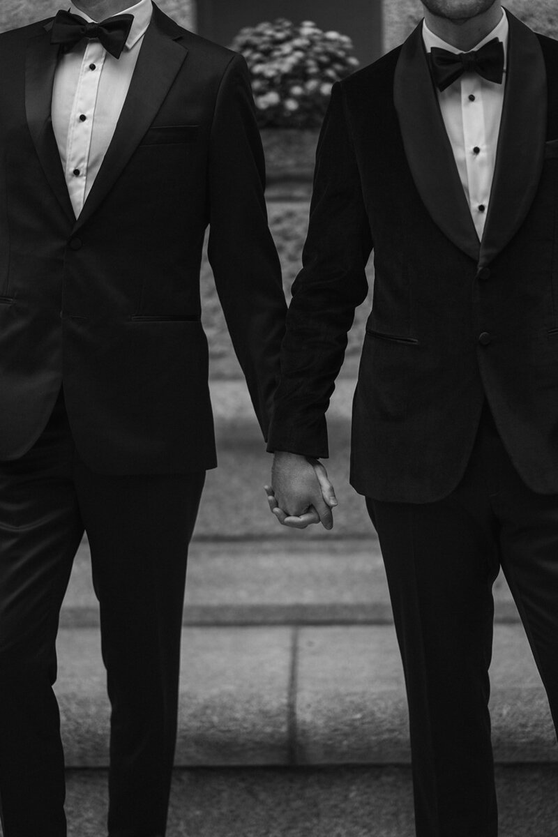 Couple holding hands wearing tuxes
