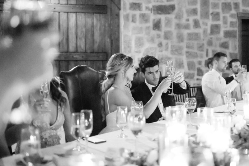 black and white photo of a bride and groom toasting to one another with their champagne glasses at swiftwater cellars