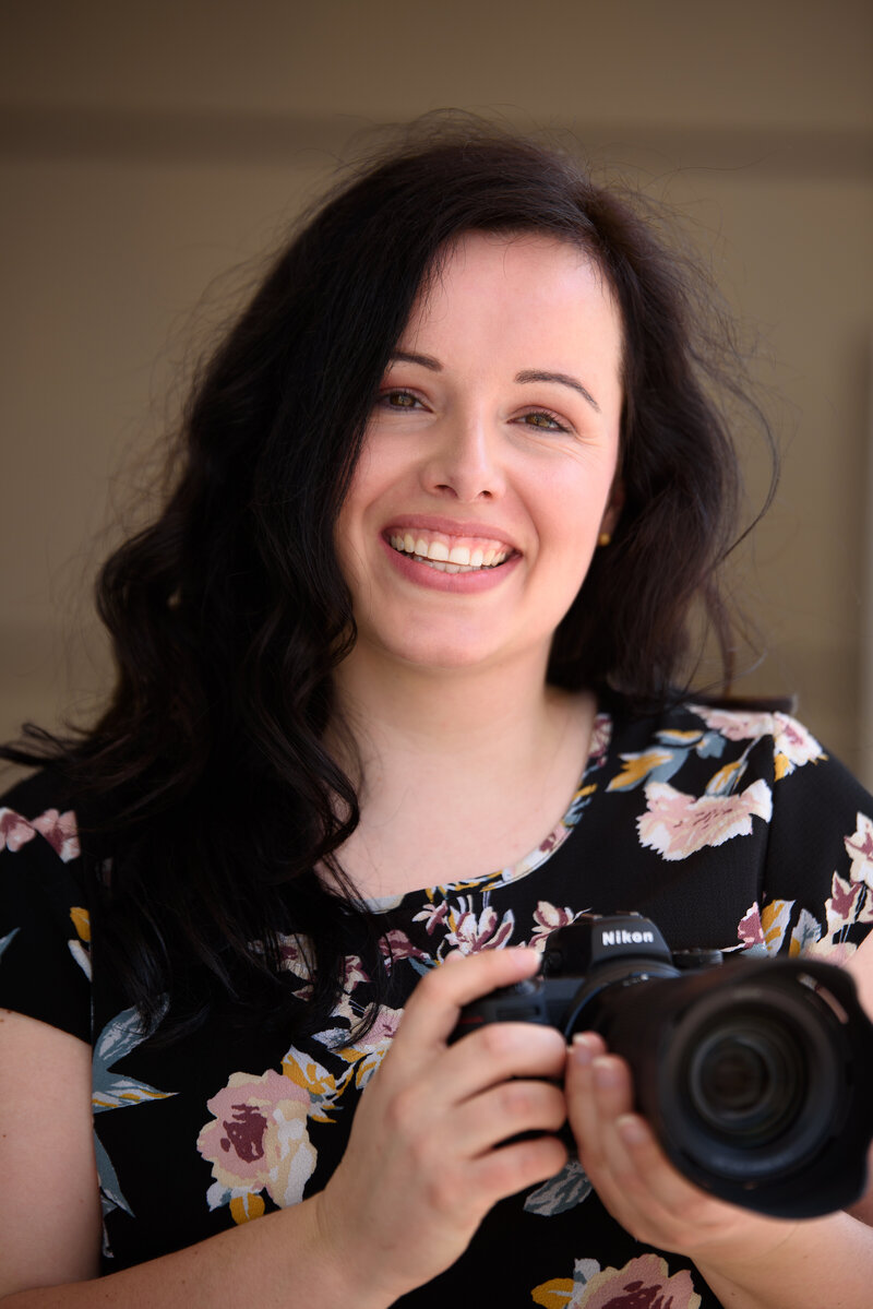 Hochzeitsfotografin mit Kamera in der Hand lächelt in die Kamera
