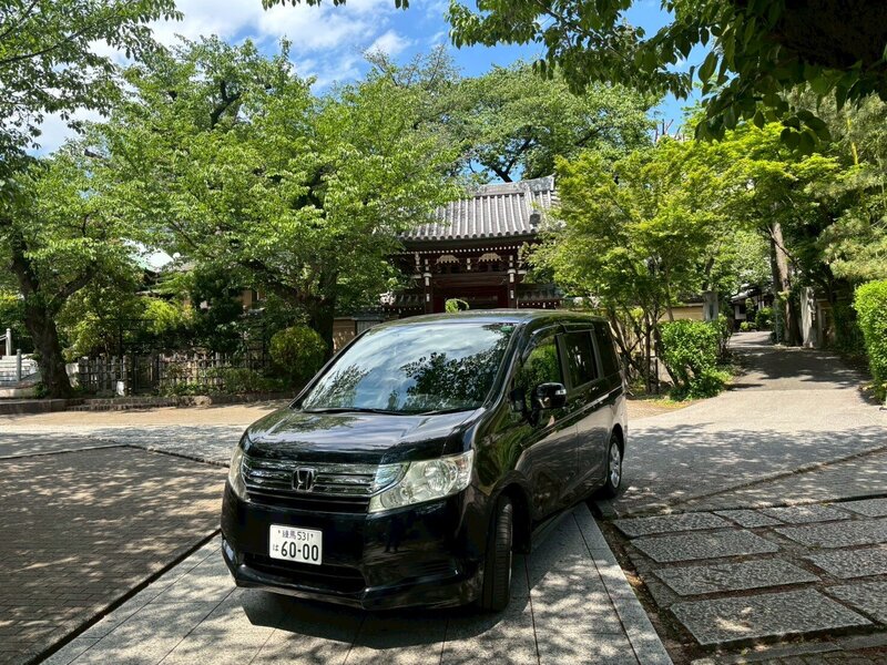 Side view of the Honda Stepwagon parked in front of a serene Japanese temple, blending modern luxury with cultural heritage.
