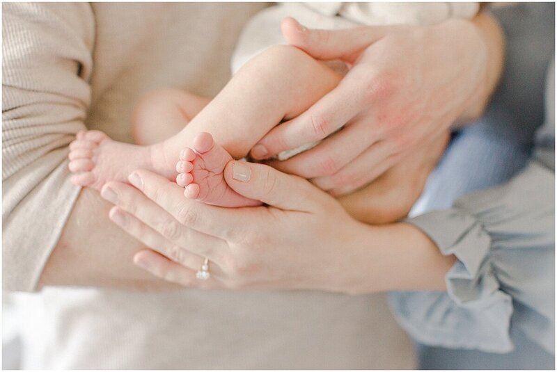 Detail photo of newborn baby feet with mom and dads hands