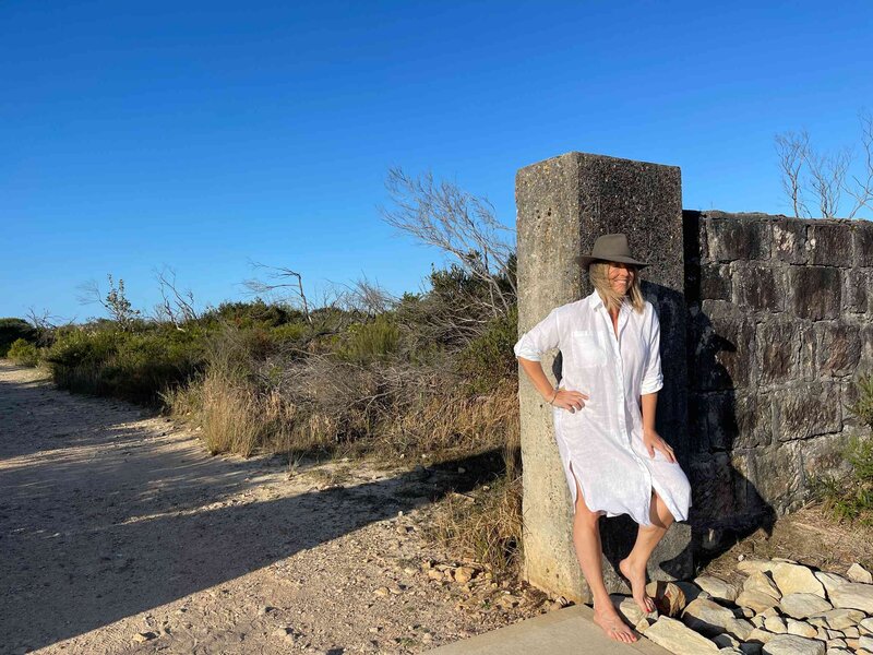 rebecca wearing hat and white dress outside