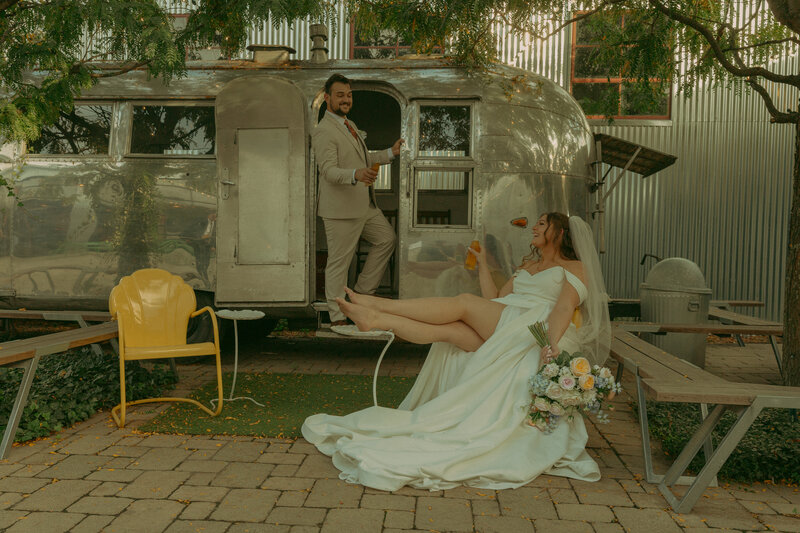 Newlyweds gaze into eachothers eyes on a brisk summer evening while the sun glares between their faces and her veil gets carried in the wind