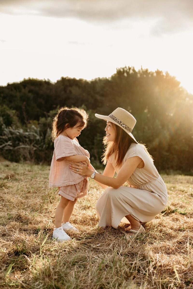 A mother and daughter holding onto one anothers hands while they pose for auckland photographer michelle kelly