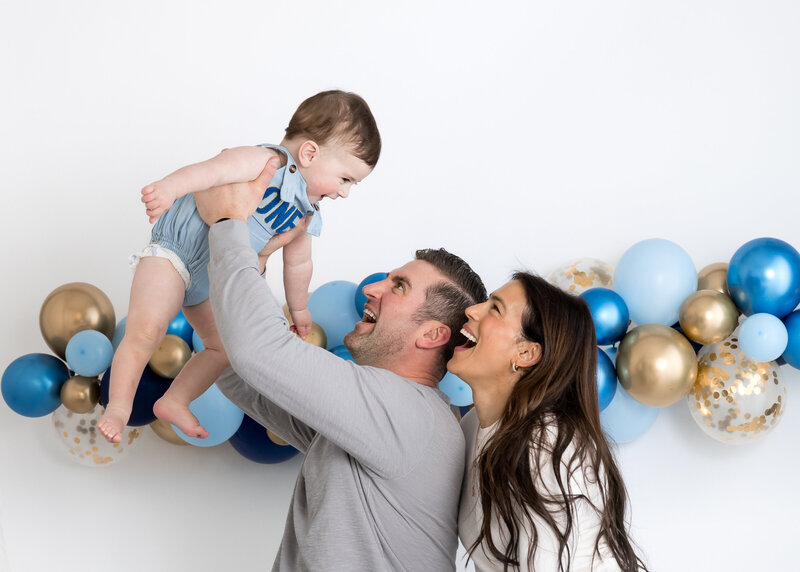 Light and airy lifestyle portrait of a family at a 1st birthday cake smash photo session at Allison Reilly's Union County, NJ photo studio.