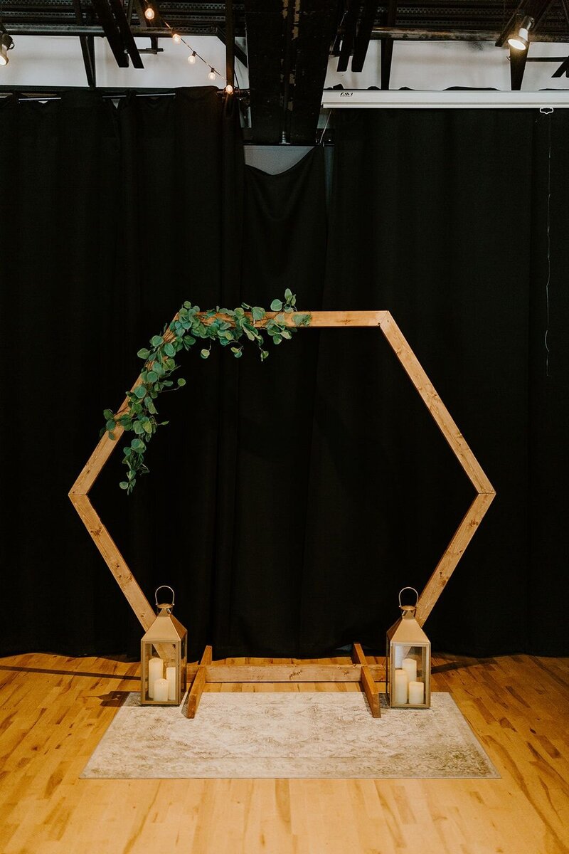 Hexagon arch for a wedding ceremony with greenery and lanterns
