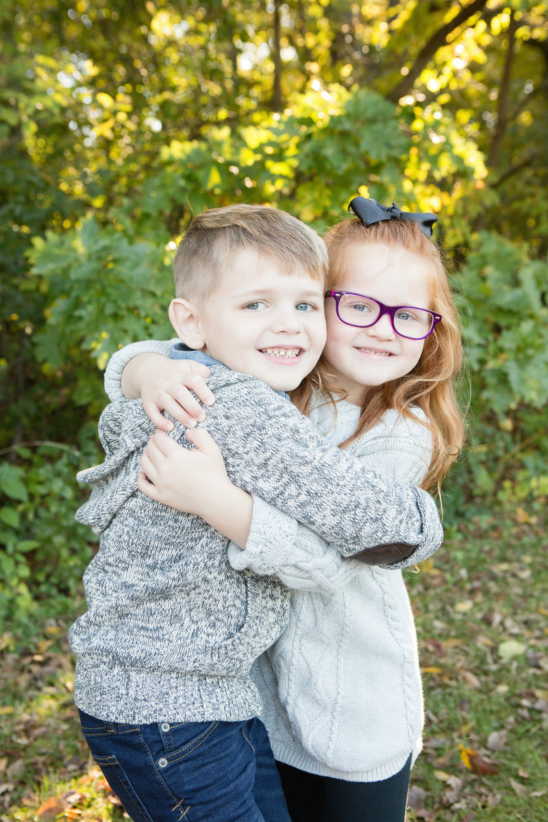 Brother and sister hugging in front of trees