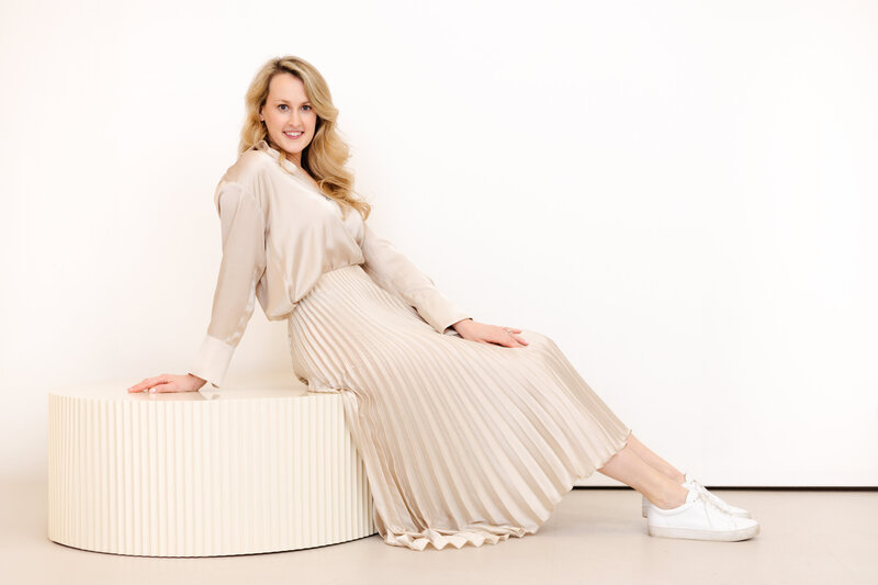 Valerie Greene sitting on white bench in soft pink outfit