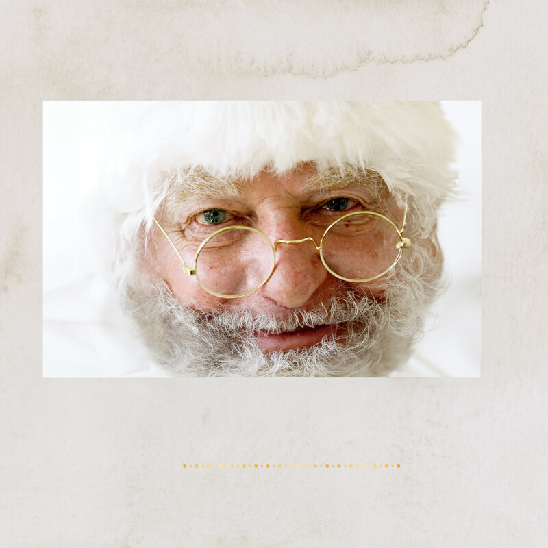 Close up of Santa Clause looking over his gold rimmed glasses at the camera