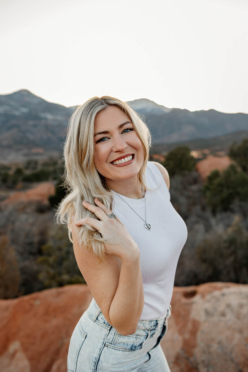 Michelle a Colorado wedding and elopement photographer smiling to the camera. With Garden of the Gods red rocks in the background.