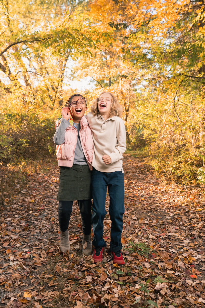 siblings laughing with fall foliage in background