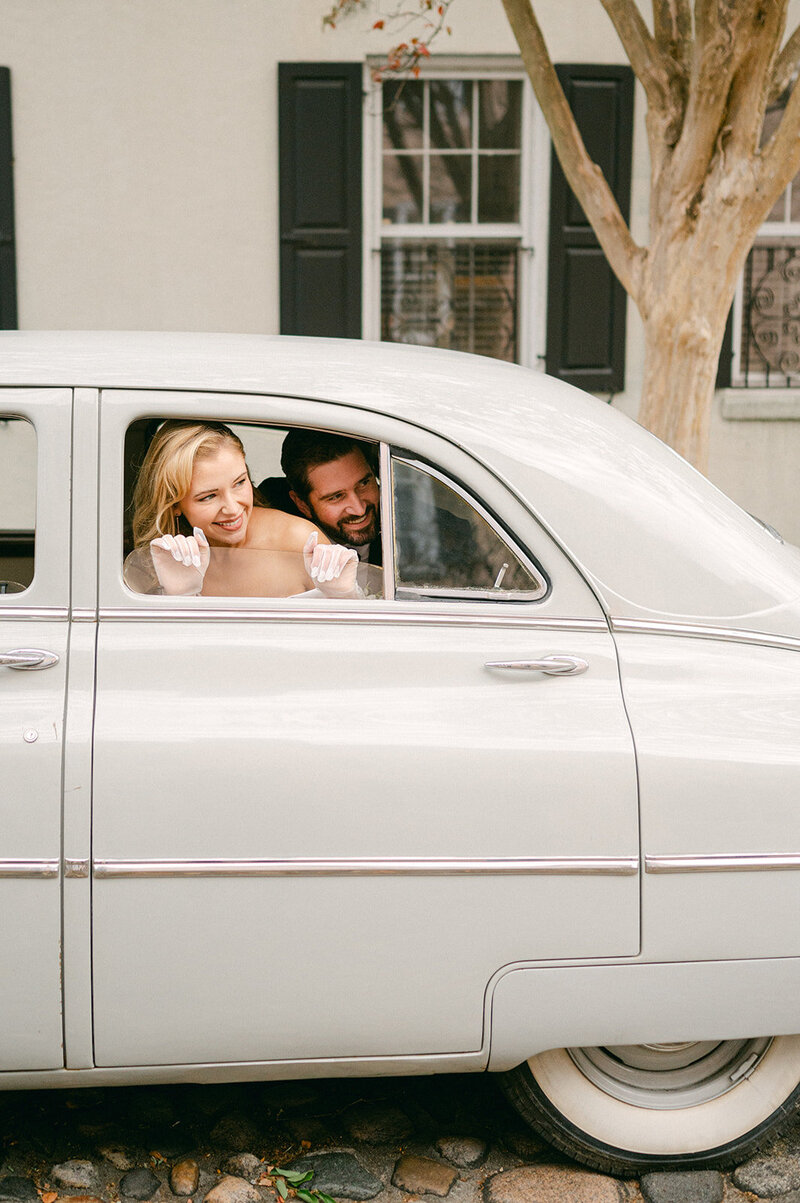 Bride and Groom peek out of their getaway car window after their wedding ceremony in Charleston, SC.