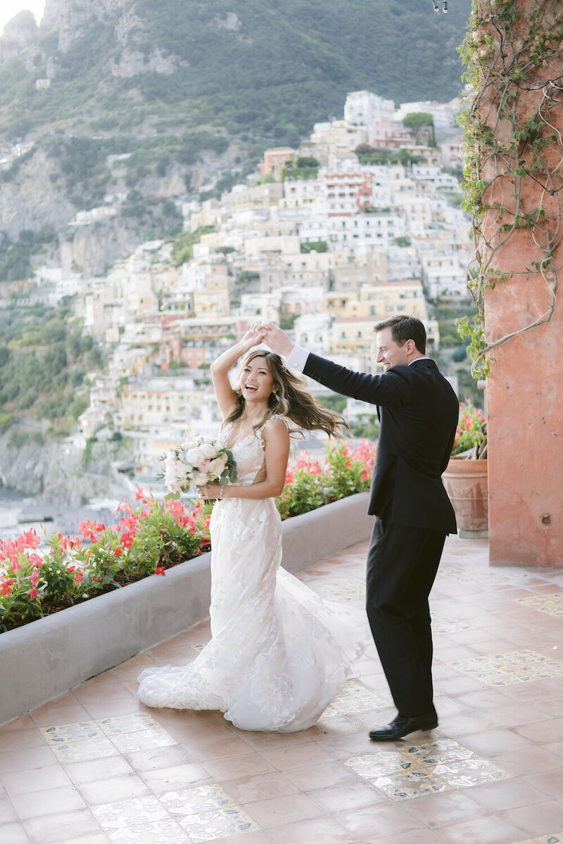 bride and groom dancing with Positano hillside in background