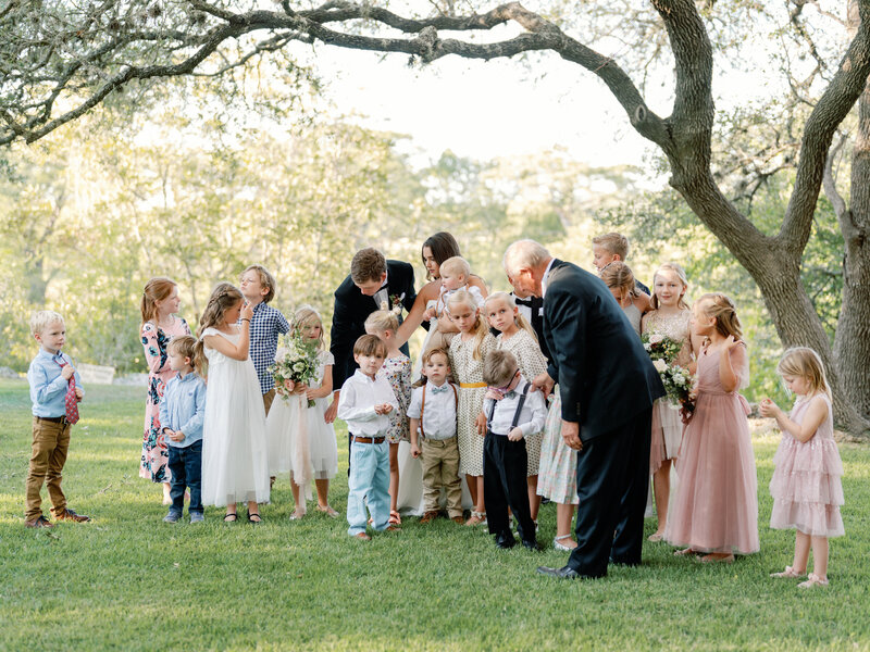 Bride and groom posing with all of the kids in their family and wedding party