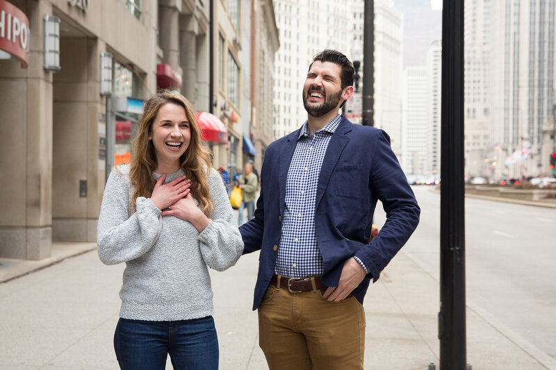 couple laughing after surprise proposal woman gasping from surprise engagement downtown chicago mag mile