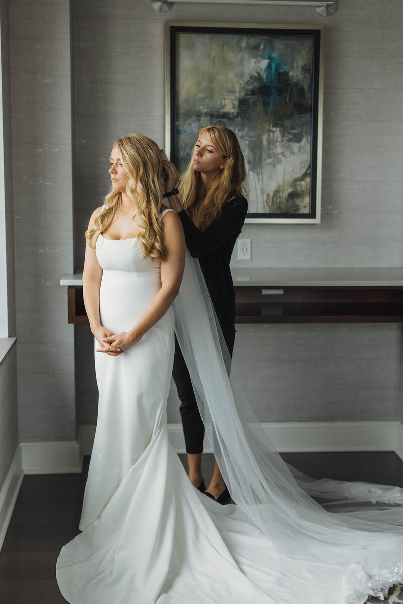 wedding planner helping to adjust bride's veil in hair