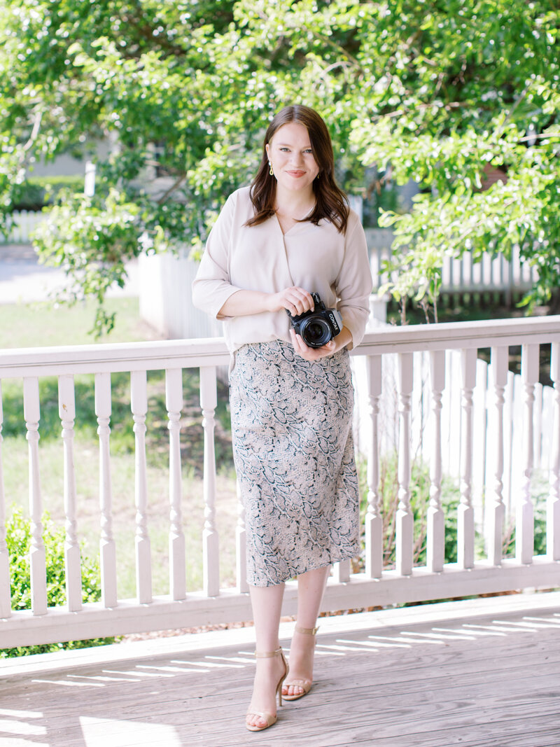 Fine art Tulsa wedding photographer Laura Eddy taking branding photos in Oklahoma City wearing a black shirt and snake skin pattern long skirt holding a contax 645 medium format camera