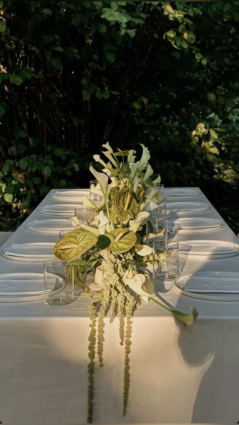 Intimate outdoor dinner party at dusk featuring a table runner of ivory and green statement florals.