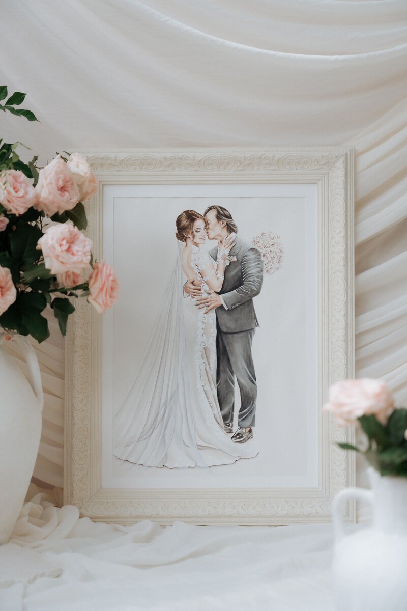A hand-painted wedding illustration of a couple in a tender embrace, surrounded by pink roses and greenery, framed elegantly.