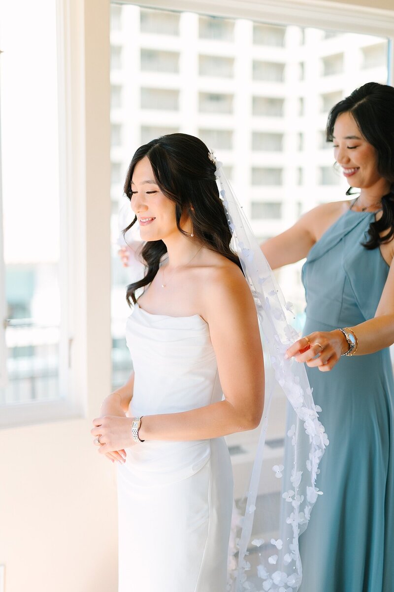 Bridesmaid helping the bride put on her veil at Darlington House in La Jolla, California.