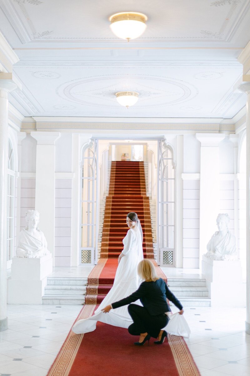 ECLAT Destination Wedding member assisting the bride with her wedding gown while posing for her bridal portrait at palace Albertina in Vienna
