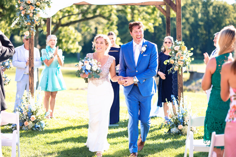 A happy wedding couple holding hands walking down the aisle at the Sylvania Country Club