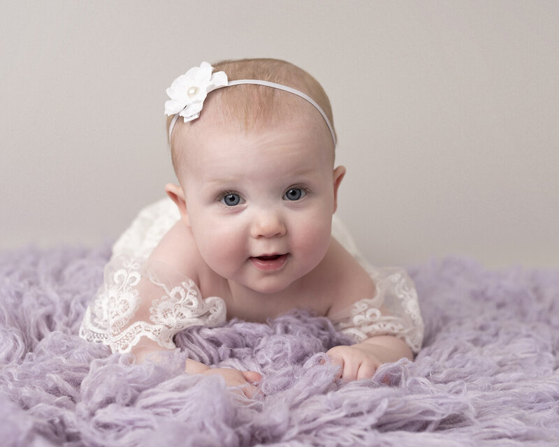 Pretty blue eyed baby on lavender rug for her milestone photoshoot