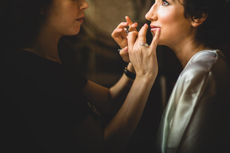 bride having her makeup done before the wedding ceremony