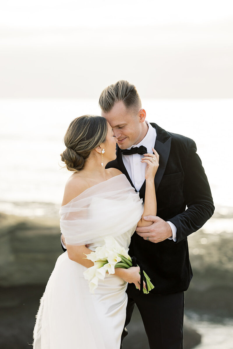 Bride romantically holding her groom on top of a cliff