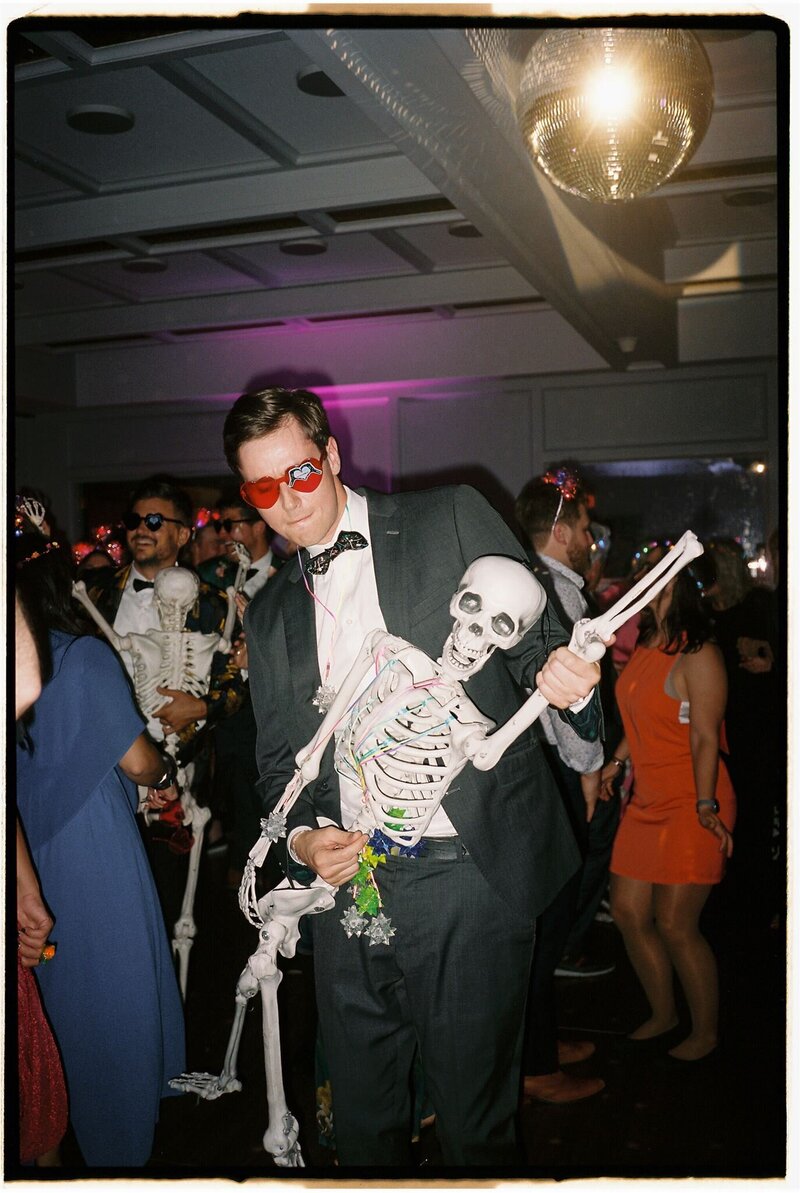 Wedding guests dancing on the dance floor in the ballroom at the Line Hotel DC with a black suited male dancing with a skeleton