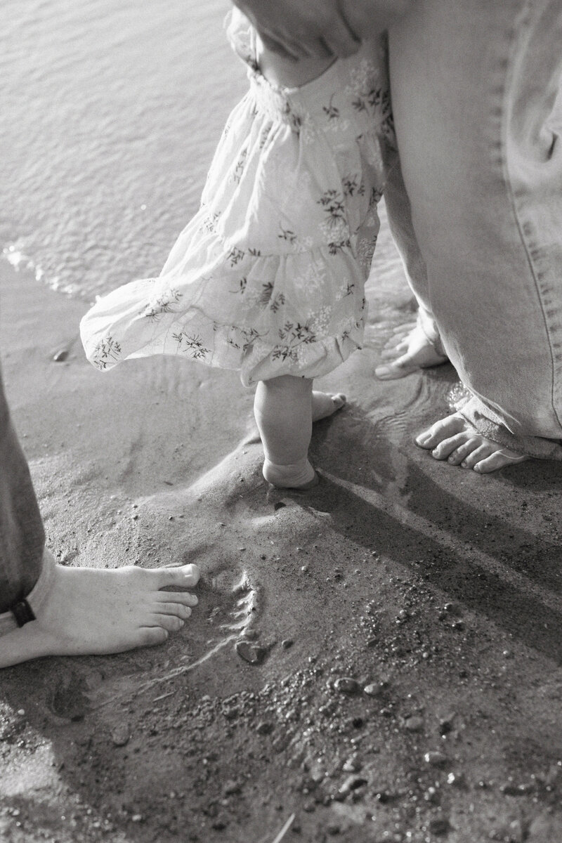 black and white detail photo of family with their feet in the sand