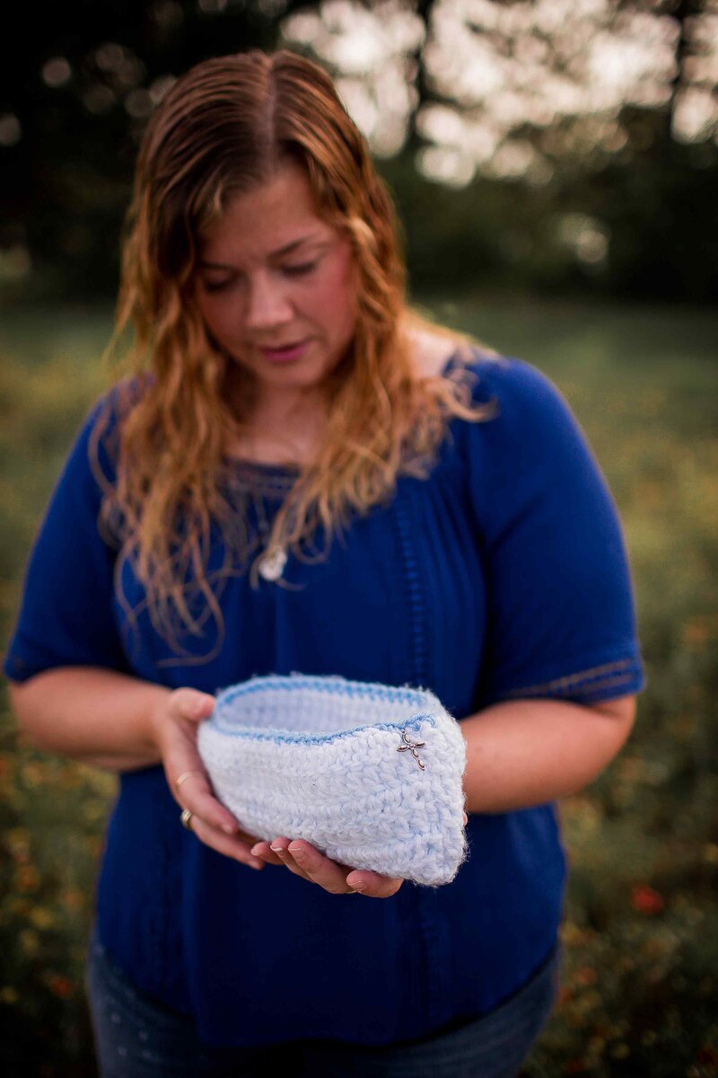 grieving mother holds crochet cradle in memory of baby boy in Heaven