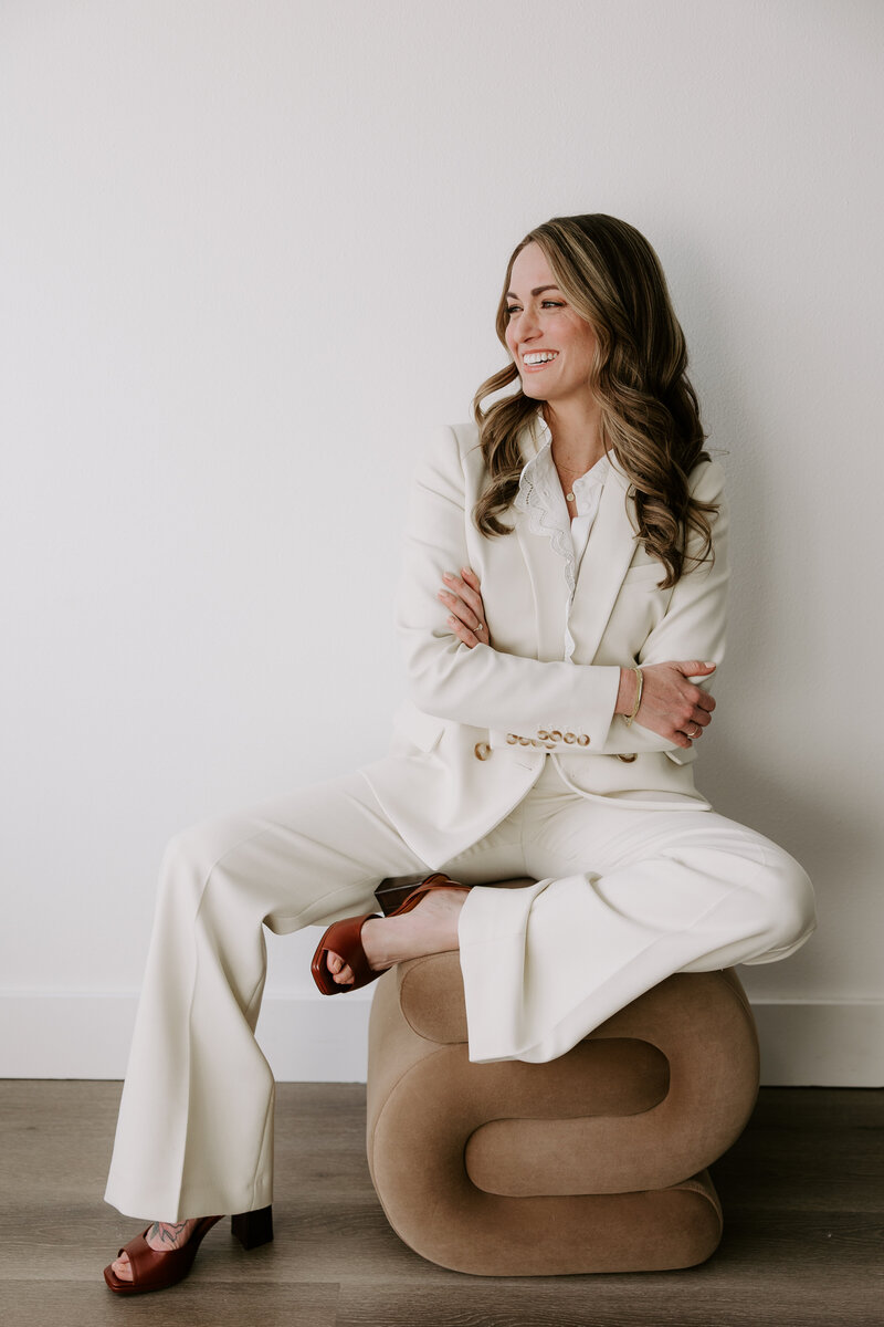 Studio portrait of website copywriter Erika Fitzgerald wearing a white suit in front of a white background, reflecting the clarity and confidence clients gain from a website copy audit
