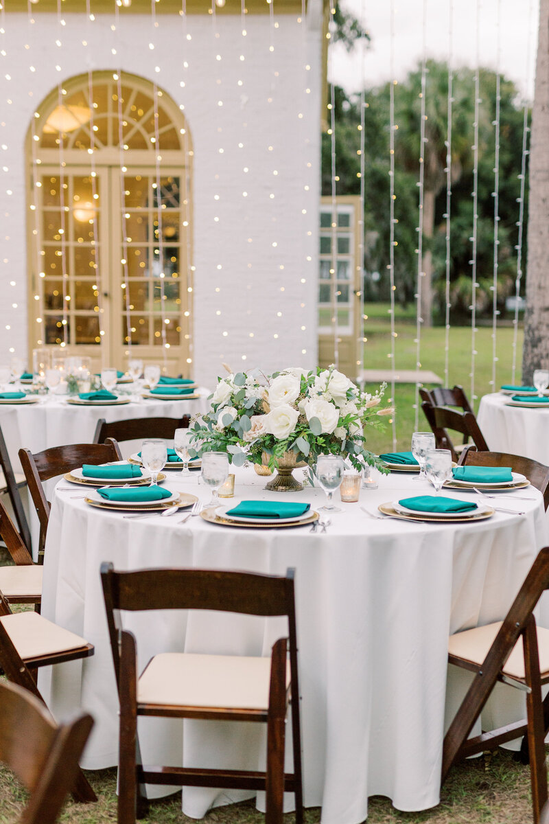 Elegant outdoor wedding reception under string lights with white florals and emerald napkins, styled by The Eventful Gals.